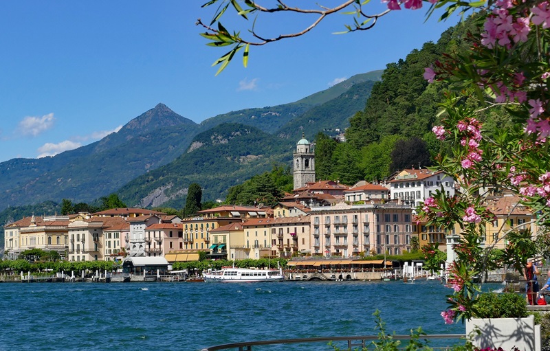 Deep blue lake Como with village buildings and a large boat